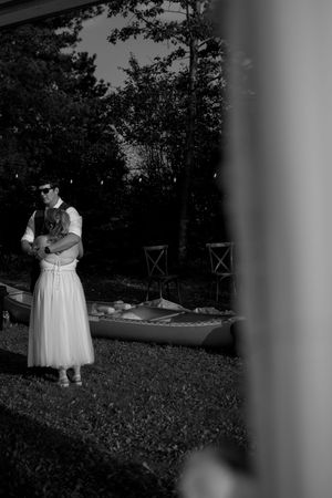 Black and white photo of figures in formal attire standing on grass.