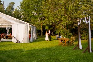 A scenic outdoor wedding venue with white tents and trees set up on a grassy lawn.