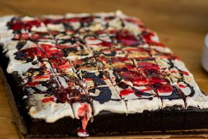 Close-up of a chocolate dessert decorated with red berries and white cream swirls.