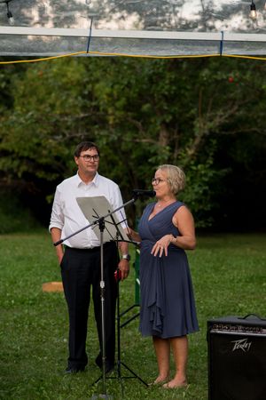 Musicians perform at an outdoor wedding reception under a canopy.