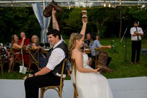 Wedding reception guests dance and celebrate under an outdoor tent on a summer evening.