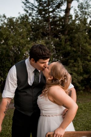 Newlyweds share a romantic kiss during their outdoor wedding celebration.