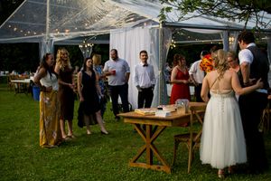 Wedding guests mingle under a clear tent during an outdoor reception.