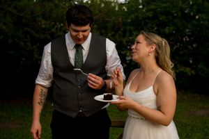 A couple enjoys dessert together at their outdoor wedding reception.
