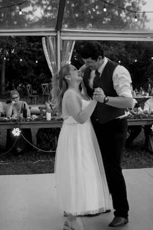 Wedding couple dancing together under an outdoor tent during their first dance at a garden reception.