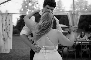 Couple shares an intimate dance moment under twinkling reception lights.