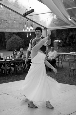Black and white photo of dancing at a wedding reception under a tent.
