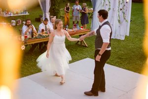 Wedding reception under string lights with guests mingling at outdoor tables.