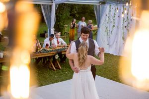 Wedding reception tent illuminated with warm string lights as guests celebrate in the evening.