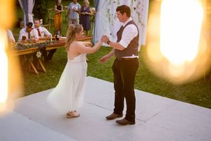 Wedding reception guests dance and celebrate on an outdoor dance floor at sunset.