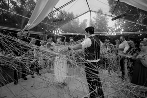 Black and white photo of wedding reception under tent with string lights and fabric draping.