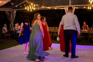 Wedding reception dance floor illuminated with warm lighting under an outdoor tent.