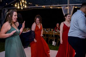 Wedding guests dance in formal attire under string lights at an outdoor reception.