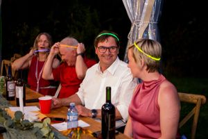 Wedding reception guests socialize and celebrate at outdoor tables during evening festivities.