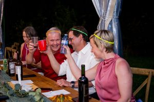 Wedding guests enjoying dinner and conversation at long tables under a tent.