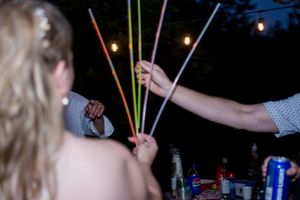 Colorful glow sticks create festive light trails at a nighttime wedding celebration.