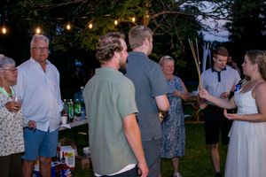 Evening wedding reception with guests mingling under string lights outdoors.