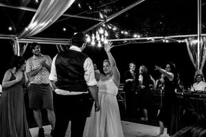 Wedding guests dancing and celebrating under draped fabric and chandeliers at an evening reception.