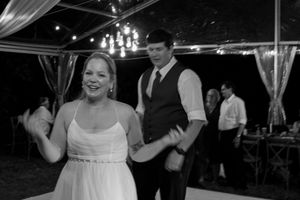 Wedding guests dance and celebrate under elegant chandelier lighting at an outdoor reception.