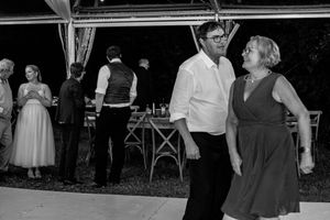 Black and white photo of people dancing at an outdoor party under a tent, with guests mingling in the background.