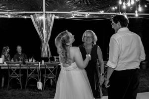 Couples dance together at an elegant evening wedding reception under twinkling lights and draped fabric decor.