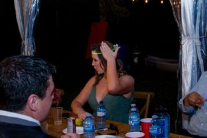 Wedding guests dance and celebrate at an evening reception under string lights and white fabric decor.