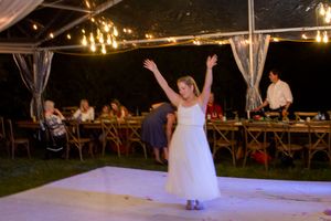 Illuminated outdoor wedding reception venue with string lights and white fabric decor.