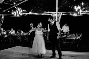 Evening wedding celebration with dance floor and ambient lighting under tent canopy.