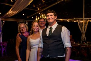 Wedding guests enjoying a festive celebration under an illuminated tent at an evening reception.