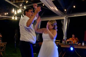 Wedding reception venue decorated with elegant white draping and warm lighting for evening celebration.