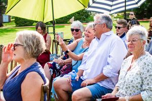 Wedding guests seated under yellow umbrellas during an outdoor ceremony.