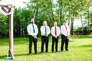 Wedding party lines up on green lawn with decorative white poles and fabric draping.