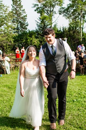 Wedding celebration on a sunny day with guests gathered on a grassy lawn.