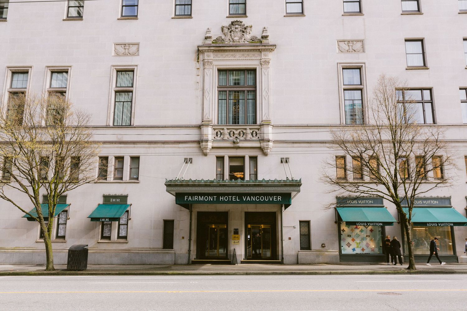 Historic white stone building facade with classical architectural details and rows of windows along a city street.