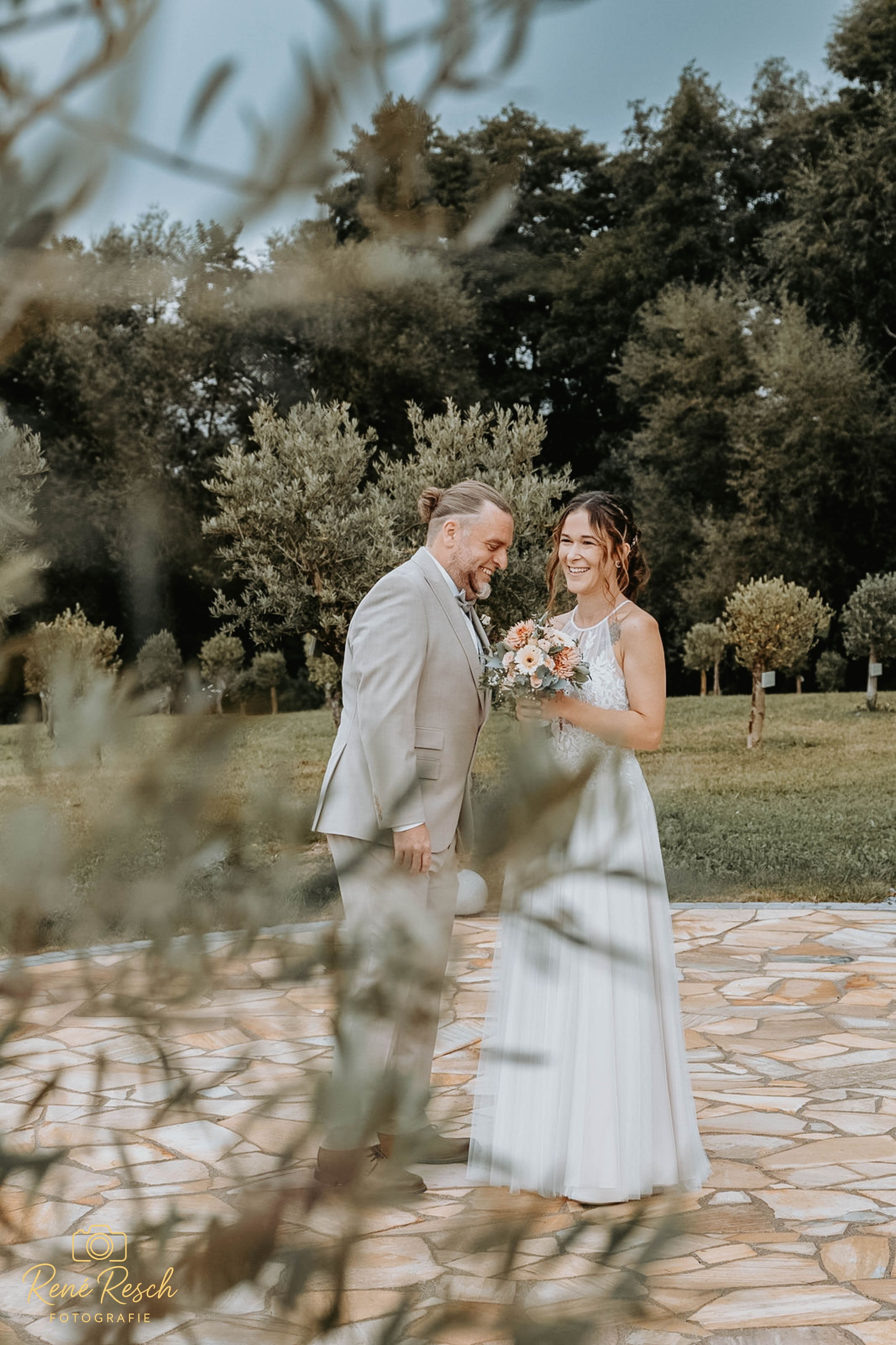 Couple shares intimate moment on stone patio surrounded by lush greenery.