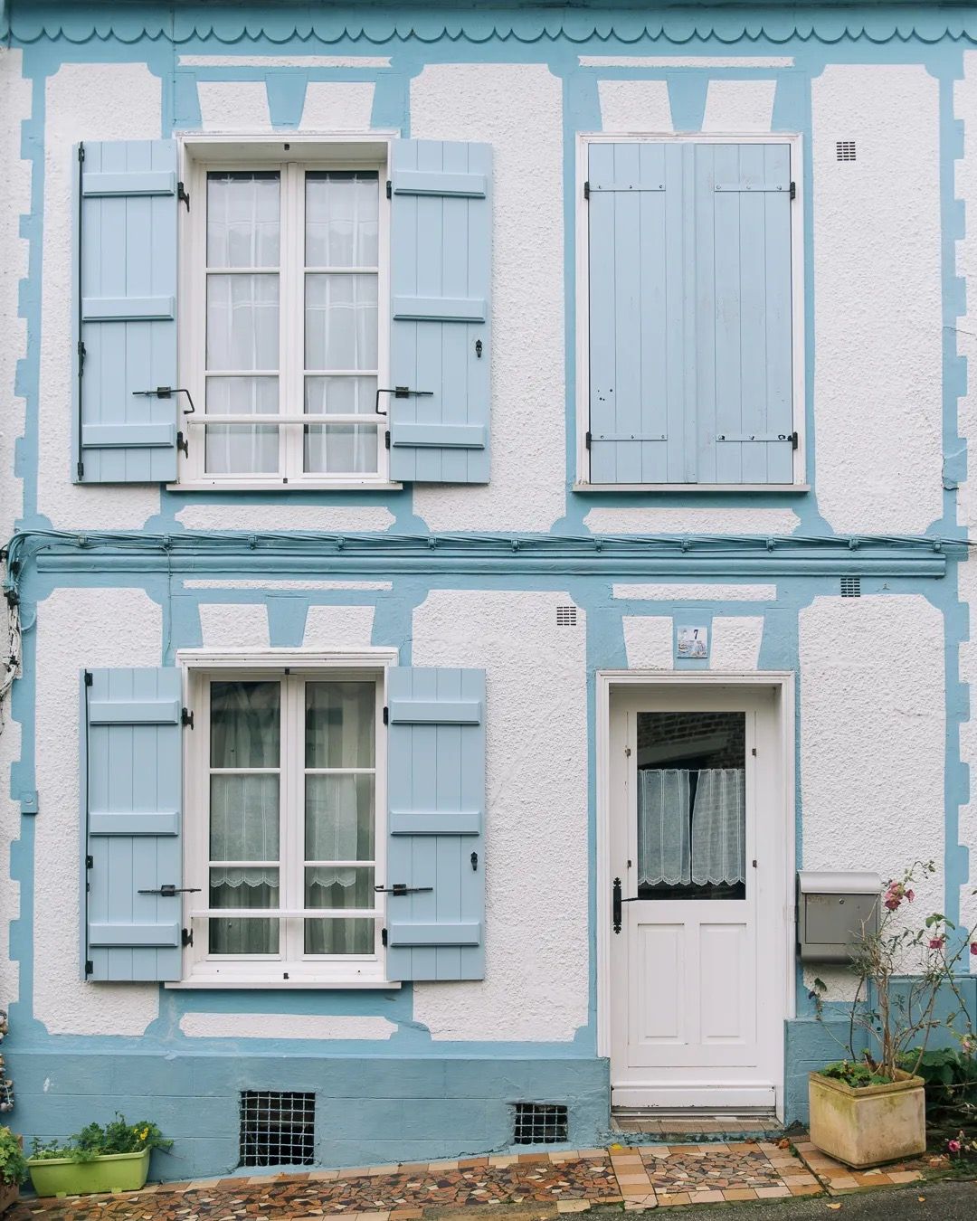 Light blue French townhouse with shuttered windows and charming pastel exterior.