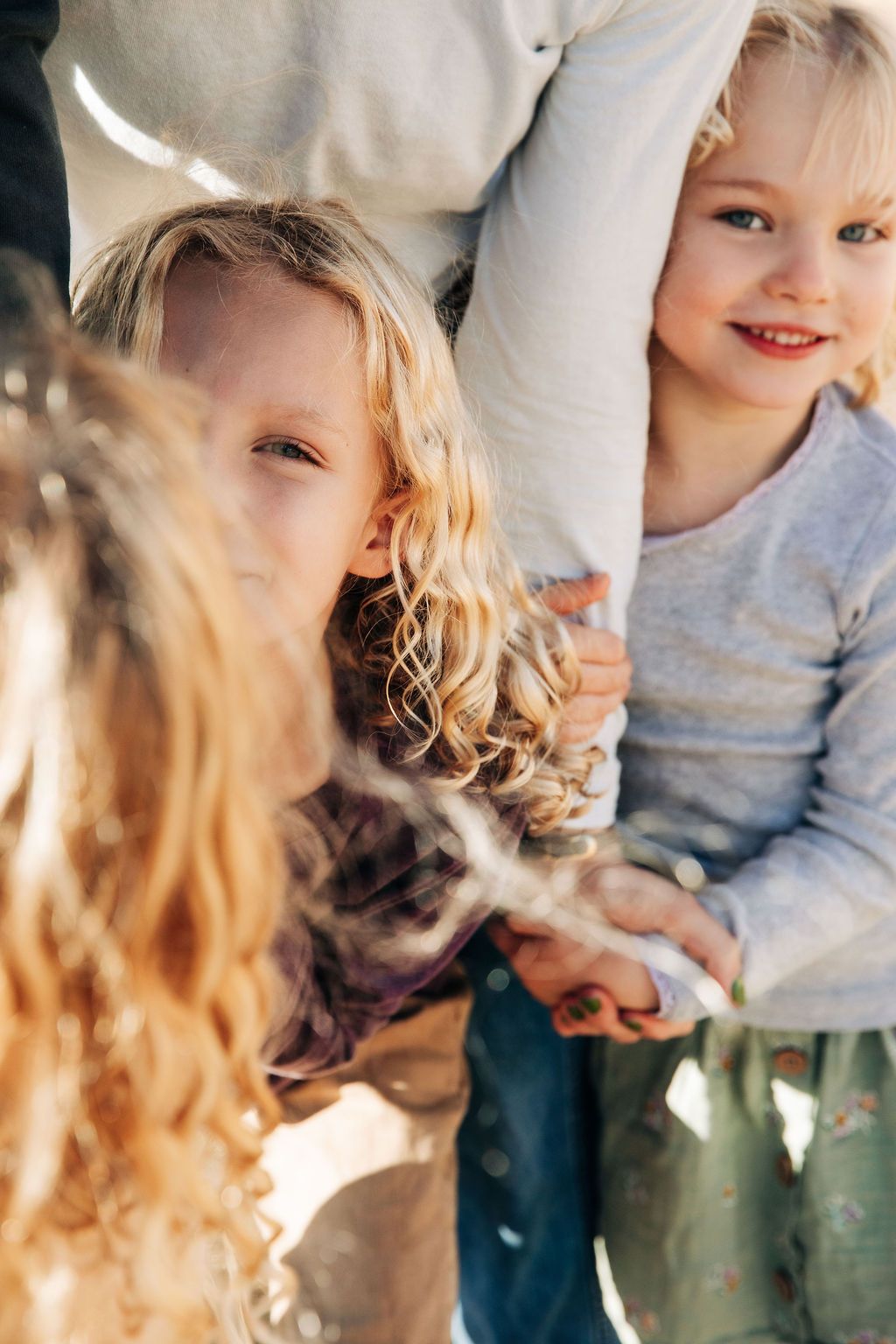 Joyful children playing together with blonde wavy hair in casual clothing.