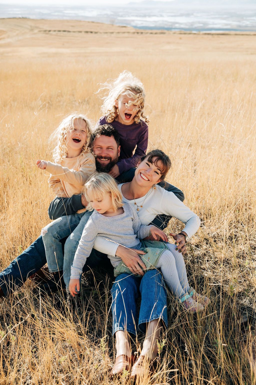 A family plays together in a golden wheat field on a sunny autumn afternoon.