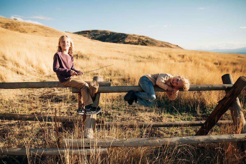 Family members laying together on dry grass hillside during sunset creating candid outdoor portraits.