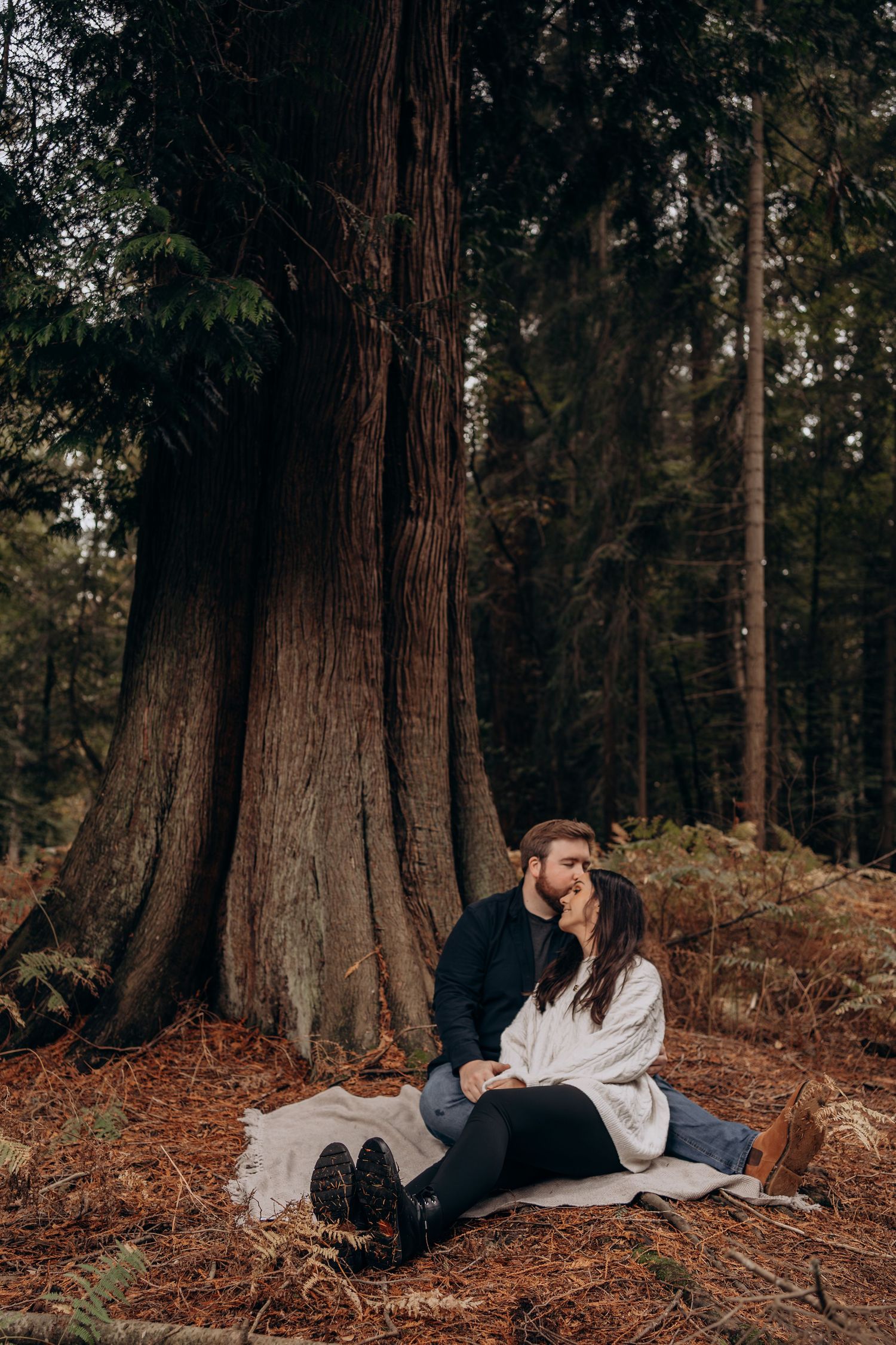 Couple embracing near a tree by a stream in a natural outdoor setting.