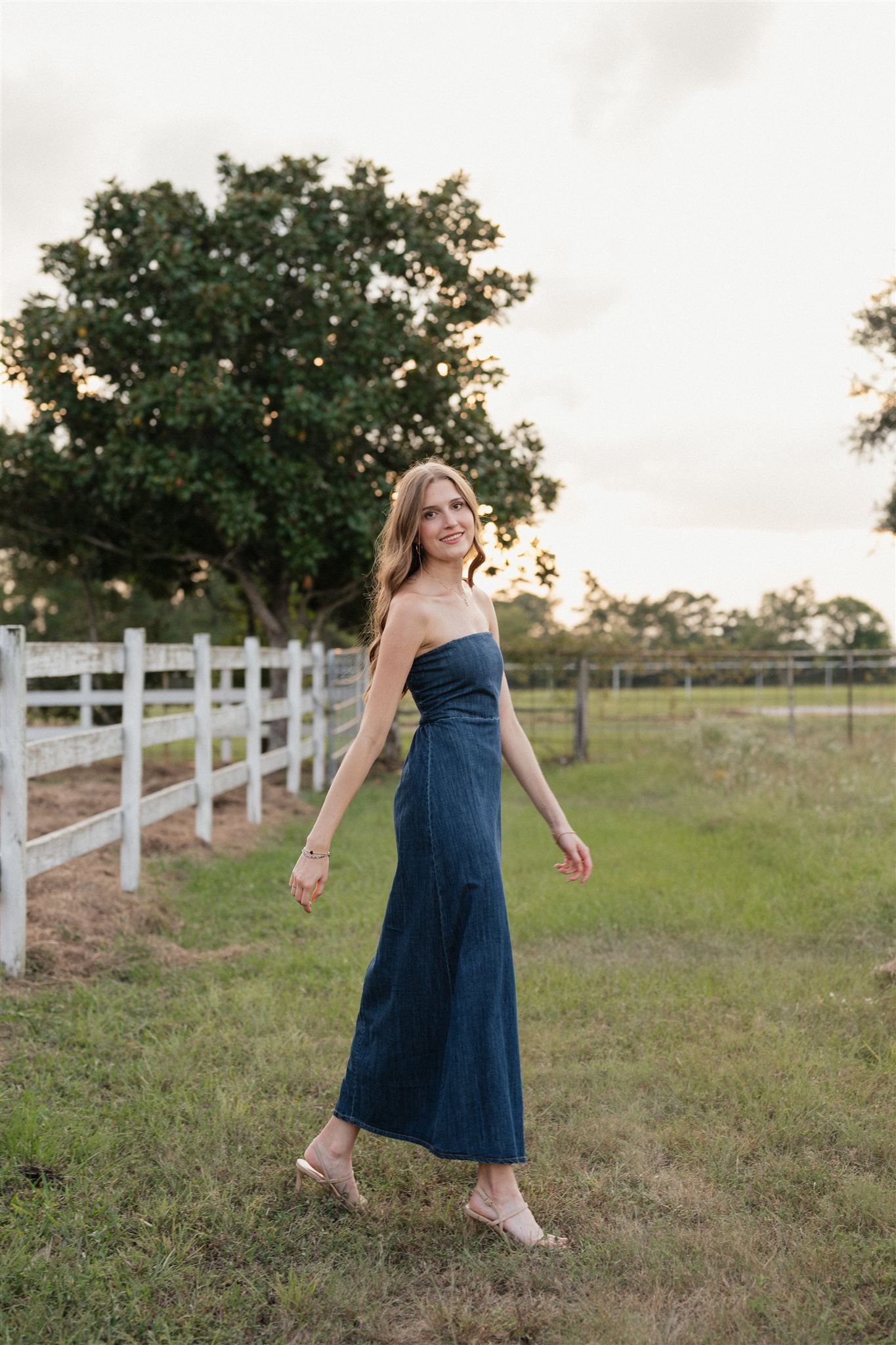 The Woodlands High School senior girl in a denim dress posing for pictures in Magnolia, Texas