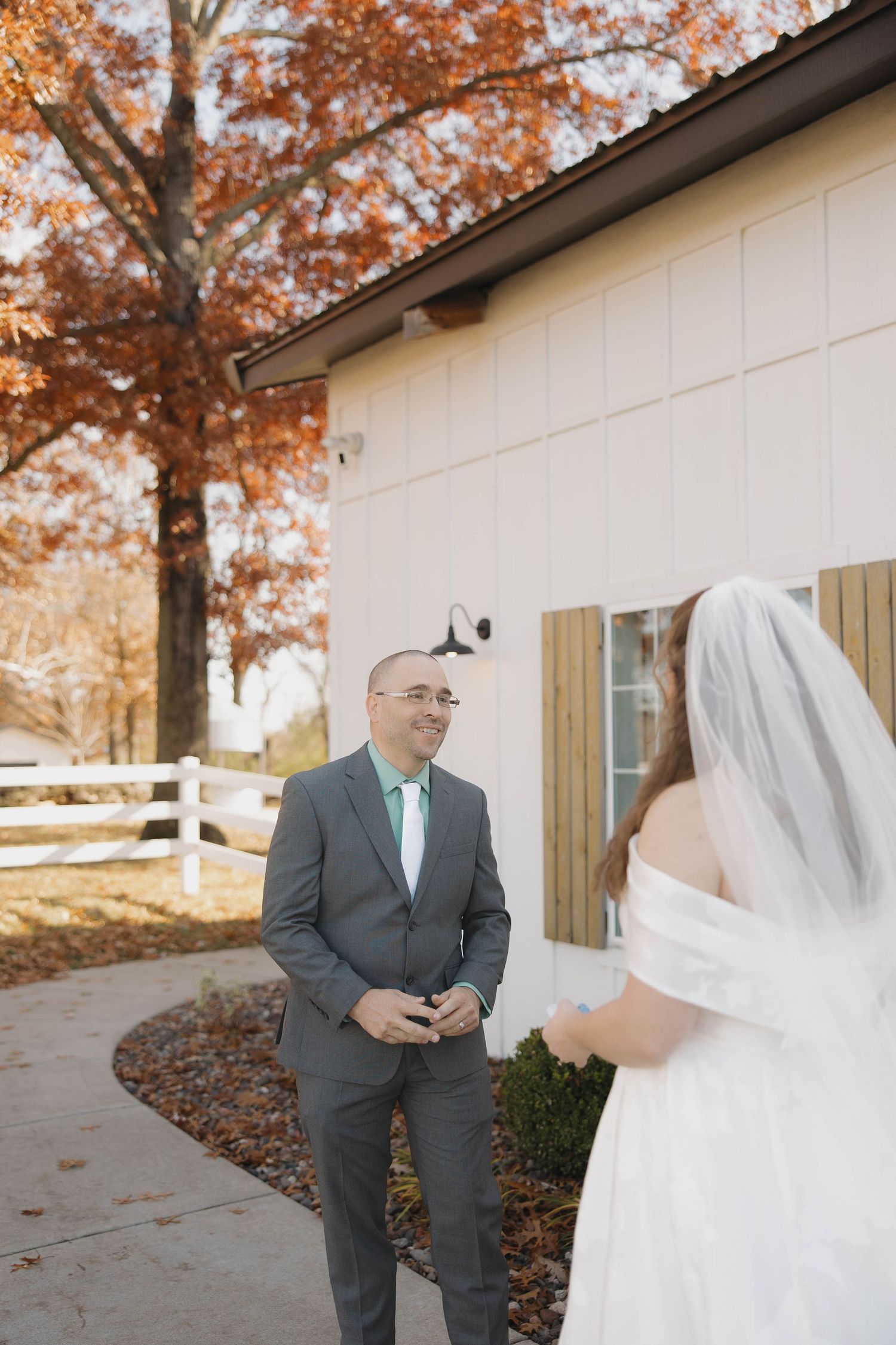 First look wedding photos of couple meeting in autumn setting with white dress and gray suit.