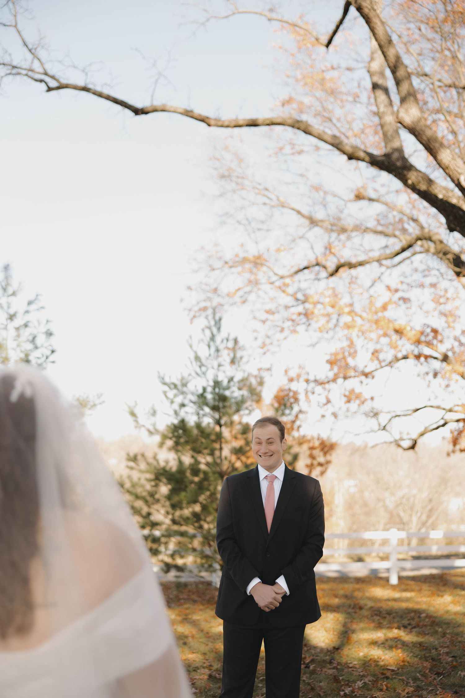Autumn wedding scene with bare tree branches and warm sunlight filtering through.