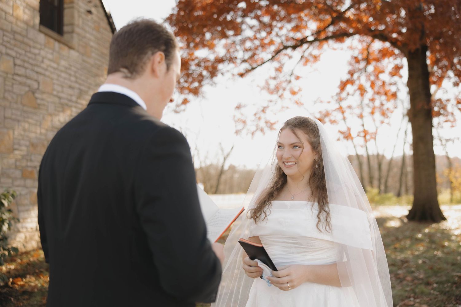 Bride and groom share intimate moments during their autumn wedding photoshoot in a park with golden fall foliage.