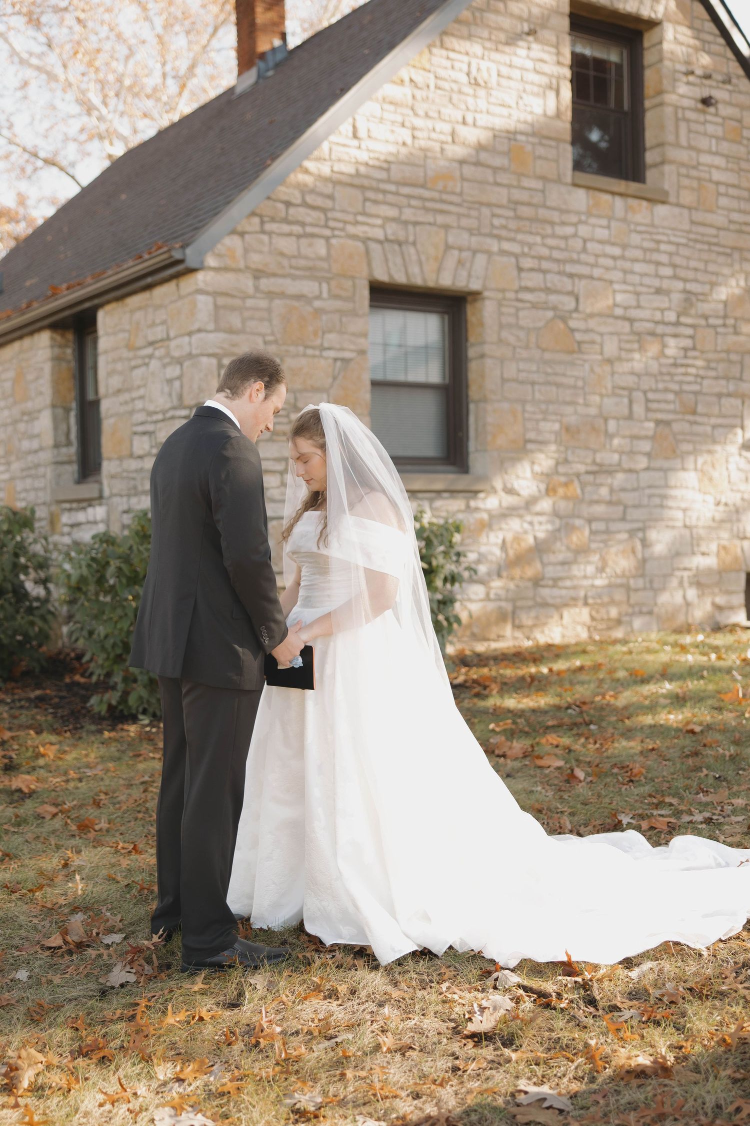 Couple shares intimate moment outside rustic stone cottage during autumn wedding.
