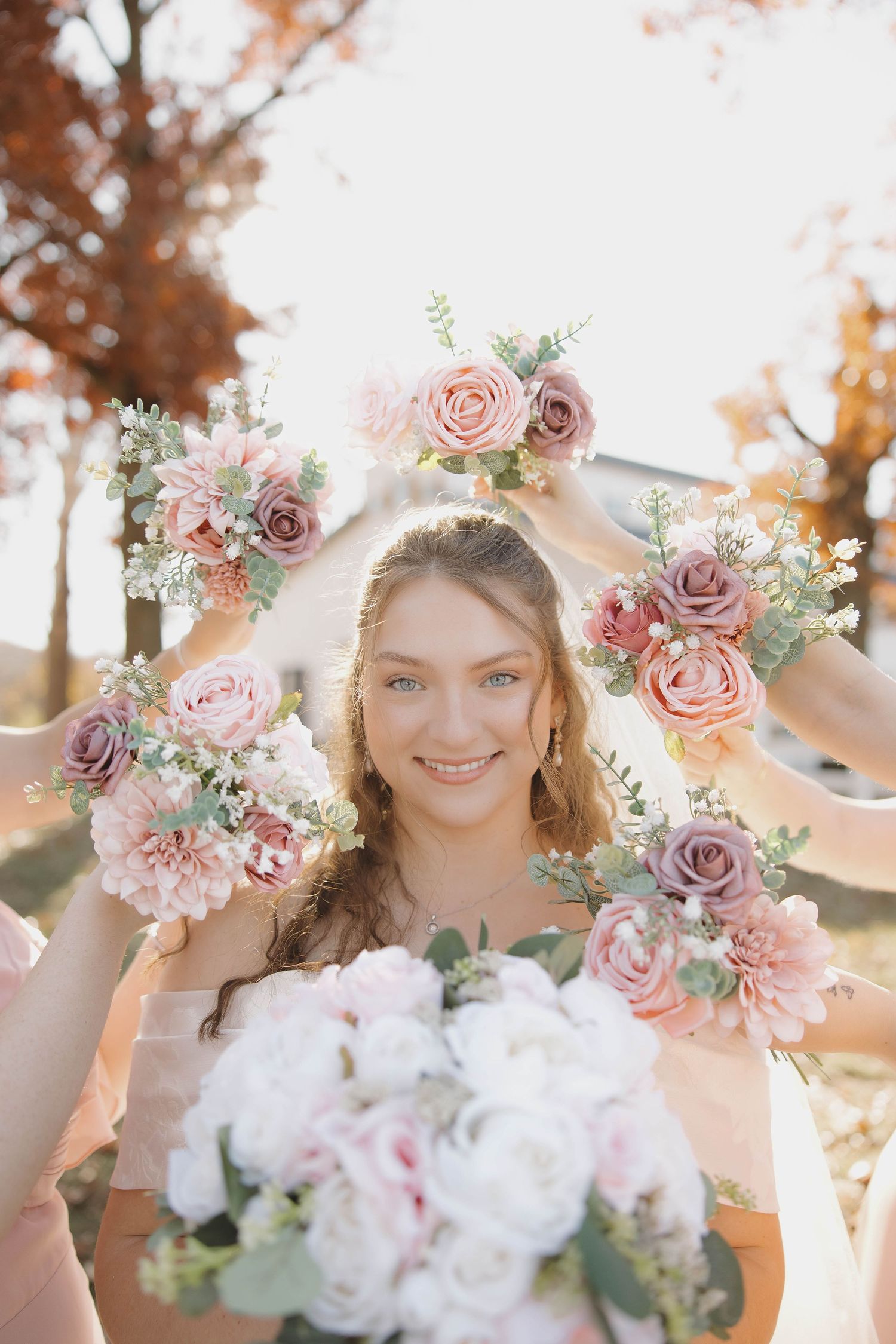 Delicate pink and mauve roses create a romantic floral crown and bouquet against an autumn sunset.