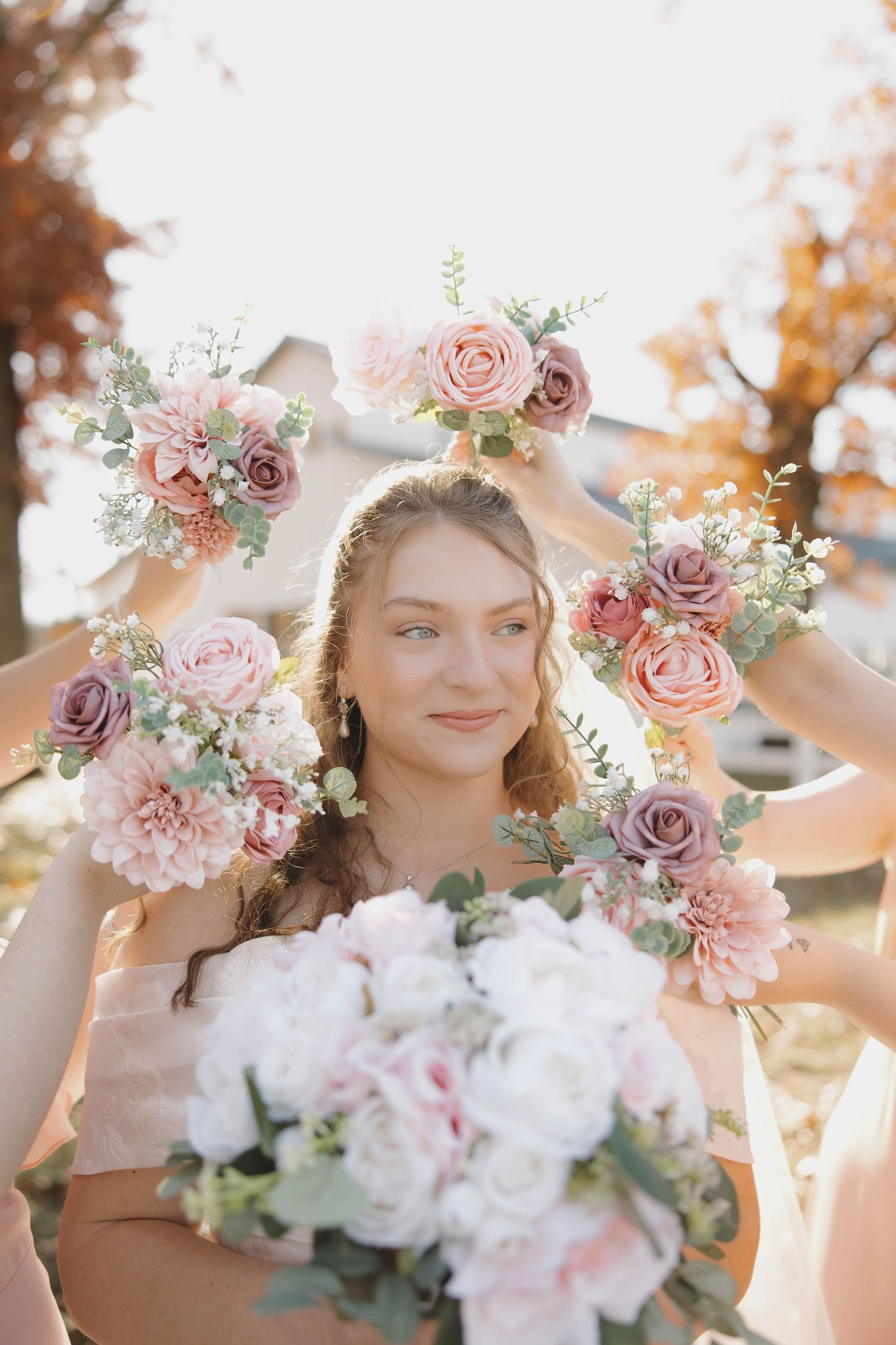 Beautiful floral arrangements with pink roses and dahlias frame wedding scene in autumn light.
