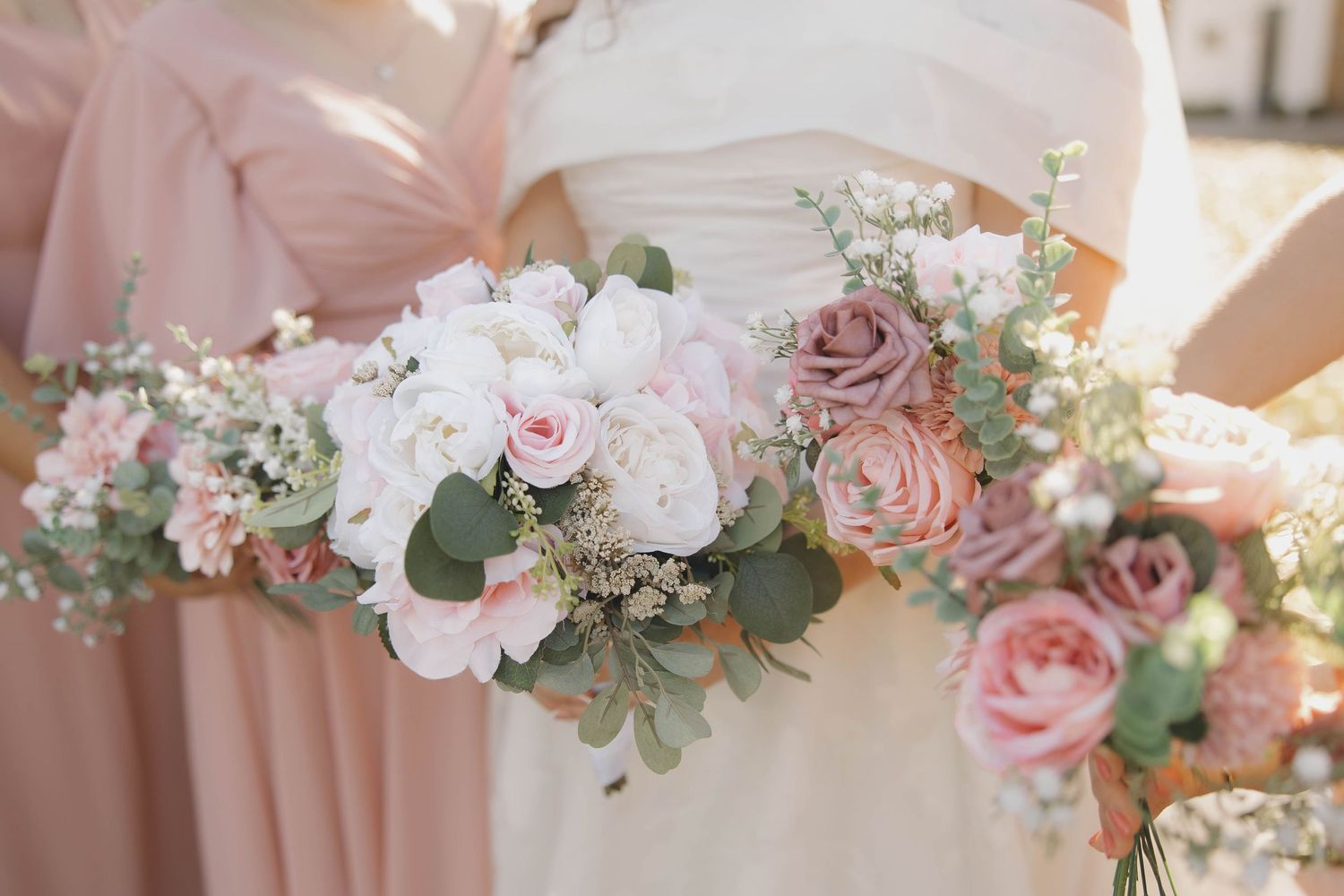 Romantic pink and white floral wedding bouquets with roses and eucalyptus arranged in a row.