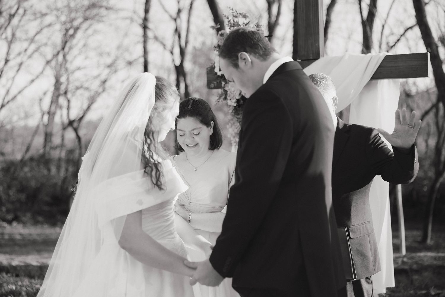 A joyful bride and groom share a candid laughing moment together during their outdoor black and white wedding ceremony.