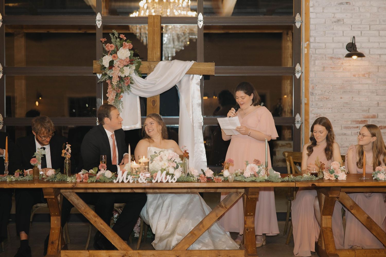 Wedding reception celebration in rustic indoor venue with exposed brick walls and wooden beams.